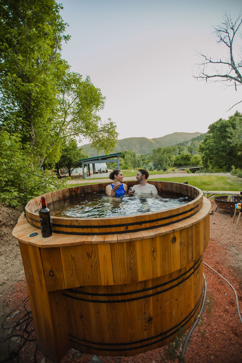 Couple enjoying the wood-fired barrel hot tub at Zen Zion with mountain views
