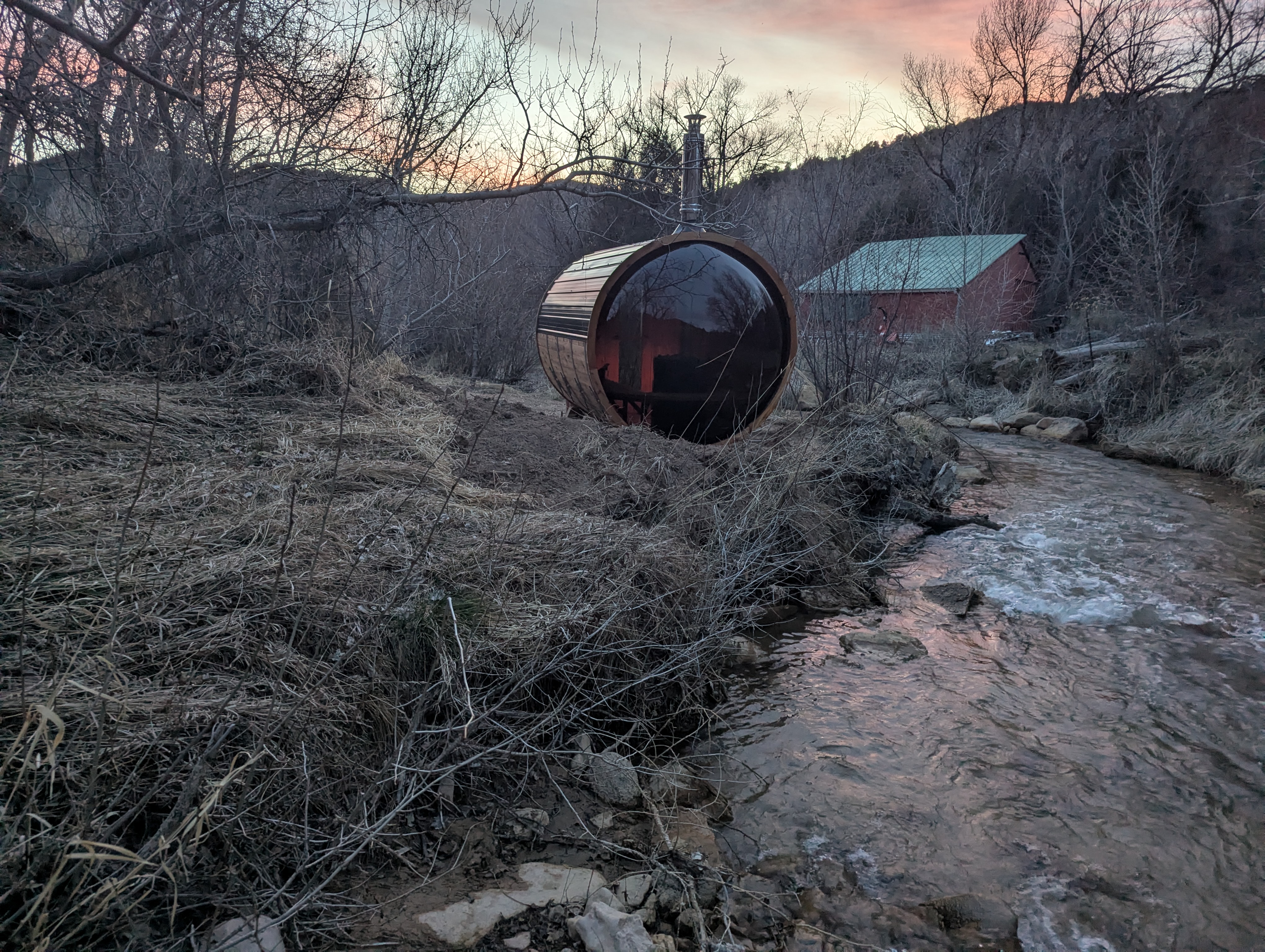 Barrel sauna perched beside the river at Zen Zion at sunset